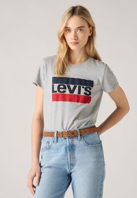 T-shirt en coton gris avec un logo Levi's audacieux en bleu marine et rouge, associé à un jean taille haute bleu clair et une ceinture en cuir marron.