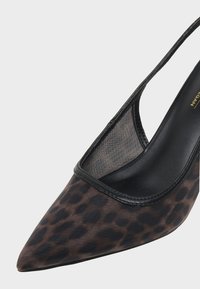 Chaussure slingback pour femme à bout pointu avec imprimé léopard marron et noir et panneau en résille noire près du talon.