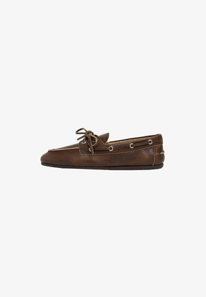 Zapato náutico de cuero marrón con cordones laterales y lazo atado en la parte superior, visto desde el lateral exterior sobre fondo blanco.