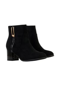 Bottes chevilles en daim noir avec talon bloc, présentant un accent latéral noir brillant et un détail en métal doré sur la fermeture éclair.