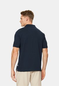 Polo shirt navy in cotone, con colletto classico, maniche corte e spacco laterale all'orlo per facilitare i movimenti.