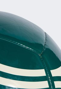 Balón de rugby verde brillante con rayas blancas, que presenta una superficie lisa, forma redondeada y costuras visibles a lo largo de las uniones.