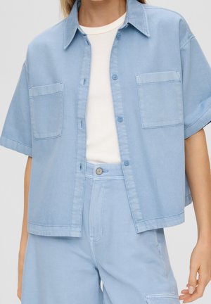 Lichtblauw overhemd met korte mouwen en knopen, met borstzakken, open gedragen over een wit geribd topje, gecombineerd met bijpassende hoge taille broek.