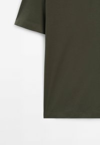T-shirt en coton vert olive à manches courtes avec couture visible à l'ourlet sur fond blanc, montrant le côté gauche et la manche.