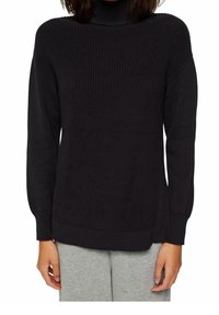 Maglione nero a maglia con collo alto, motivo testurizzato, polsini e orlo a costine. Abbinato a pantaloni della tuta grigi per un contrasto.