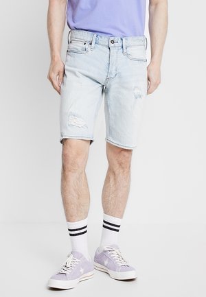 Jasnoniebieskie szorty dżinsowe z przetartymi detalami, pięcioma kieszeniami i regularnym krojem, połączone z fioletowymi trampkami i białymi skarpetkami w paski.