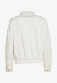 Bílá bavlněná bunda s límcem, elastickým pasem a manžetami na knoflíky. Má hladkou texturu a jednoduchý, klasický design.