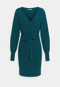 Robe tricotée bleu sarcelle avec un design portefeuille, manches longues et ceinture nouée à la taille. Présente un col en V et une texture côtelée.