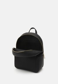 Mochila de cuero negra con un acabado texturizado, forma redondeada, cremallera dorada y un bolsillo frontal. El interior incluye bolsillos de deslizamiento para una mejor organización.