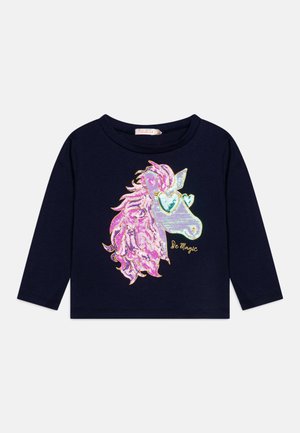 Chemise à manches longues marine avec un graphique de licorne présentant une crinière rose holographique, des lunettes de soleil en forme de cœur et le texte "Sois Magique" en doré.