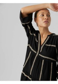 Robe noire avec broderies dorées, dotée d'un décolleté en V, d'un design superposé et de manches trois quarts. Texture douce avec des motifs décoratifs.