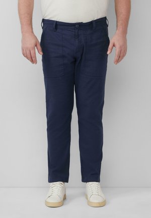 Pantalons en coton bleu marine à coupe slim, avec deux poches avant et un design à plat, associés à des baskets blanches.