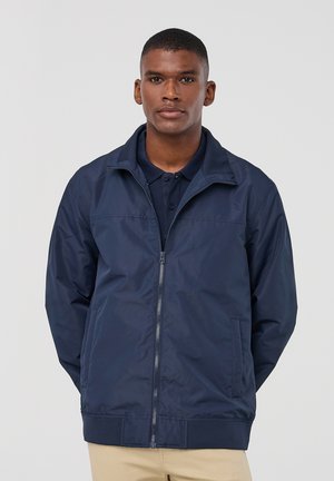 Giacca a vento blu navy, materiale leggero, chiusura con zip, colletto rialzato, tasche laterali, polsini e orlo a costine. Tessuto liscio.