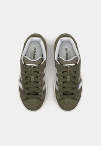 Zielone zamszowe sneakersy w kolorze oliwkowym z białą gumową podeszwą, z szarymi paskami, okrągłym noskiem i sznurowanym zapięciem. Subtelne logo na języku.