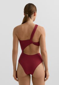 Bordo enodelne kopalke z teksturirano tkanino, enim naramnicam in odprtim hrbtnim delom s stranskim izrezom.