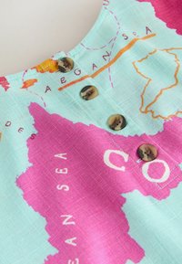 Cloth with a colorful world map print showing part of the Atlantic Ocean and buttons sewn along a central seam.