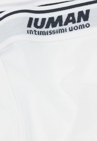 Acercamiento al cinturón de calzoncillos blancos para hombres con rayas negras y el texto de marca "INTIMISSIMI uomo".