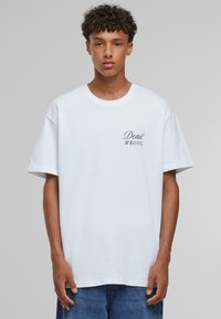 Hvid bomulds T-shirt med korte ærmer og rund hals. Har en sort "Dead WRONG" tekst på venstre brystområde. Casual pasform.