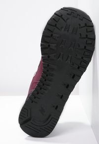 Sola di scarpa sportiva color marsala con profondo battistrada. Gomma nera testurizzata, punta curva, tallone rinforzato e dettagli di marchio vicino all'arco.