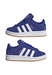 Blå ruskinnsneakers med hvite skinnstriper, rund logo på tungen og såle av gummigummi. Uformell design med lågtopp.