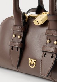 Borsa a mano in pelle marrone con due manici, lucchetto dorato sulla cerniera e emblema dorato di due uccelli su un anello nella parte anteriore.