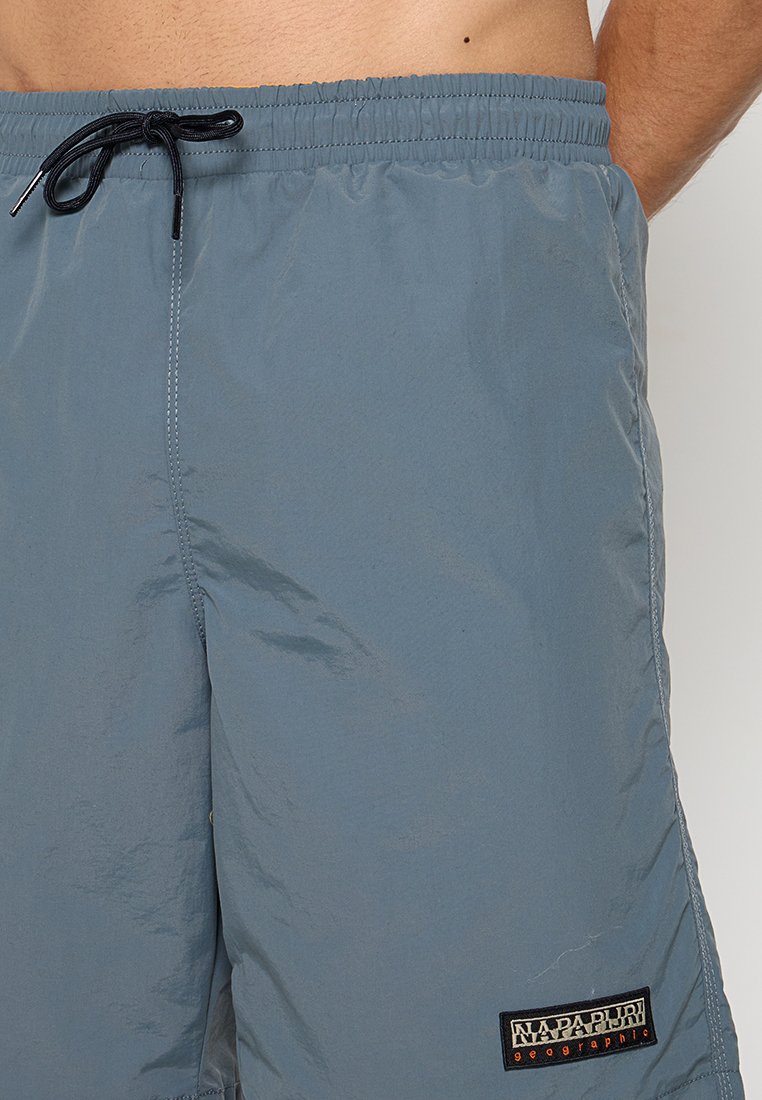 Leichte blaue Badeshorts aus glattem, feuchtigkeitsableitendem Material. Sie verfügen über einen elastischen Bund mit Kordelzug und einem Markenlogo-Label.