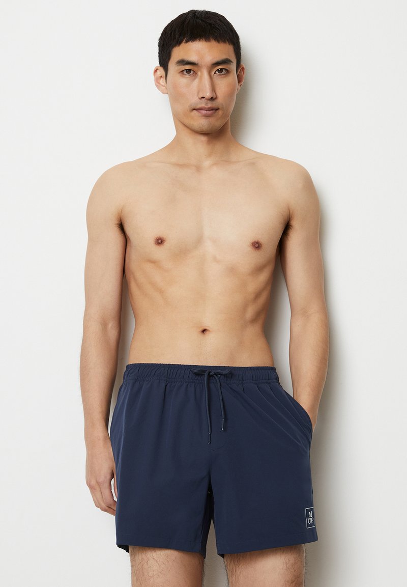 Costumi da bagno blu navy con vita elasticizzata e cordino, dotati di tasche laterali e di un piccolo logo sul pantalone sinistro.