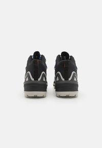 Chaussures de randonnée noires avec des semelles grises, des lacets bleus contrastants et des accents orange ; tige en tissu texturé avec un talon renforcé.