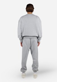 Grå sweatshirt og matchende sweatpants lavet af blødt materiale. Outfitten har en afslappet pasform, ribbede manchetter og elastisk talje.