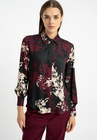 Bluzka z długim rękawem w czarnym, bordowym i kremowym kwiatowym wzorze. Posiada zapinany na guziki przód i klasyczny kołnierzyk. Gładka, jedwabista faktura.