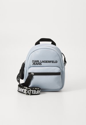 Light blue backpack made of smooth material, featuring a main compartment, front zipper pocket, and adjustable black logo strap.