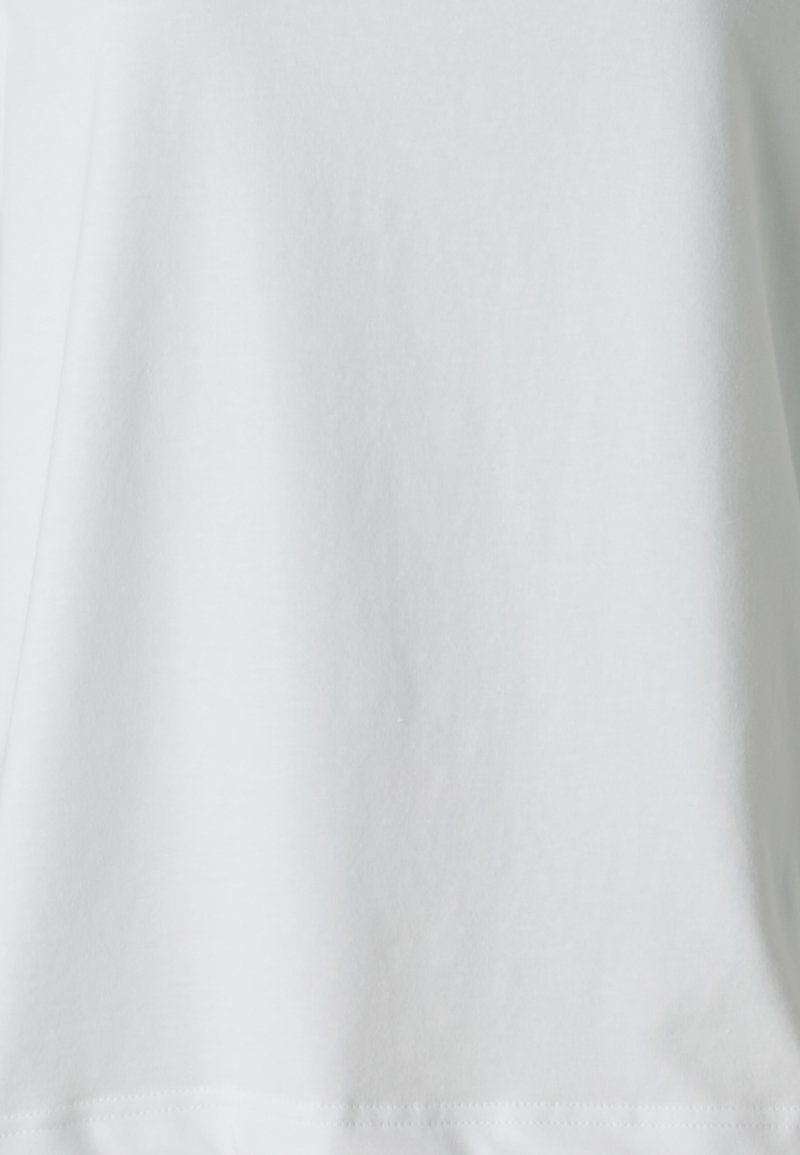 Vit bomull T-shirt med en mjuk textur, avslappnad passform och rund hals. Har en enkel design utan mönster eller synlig utrustning.