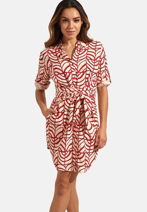 Robe à motifs rouges et blancs avec des manches courtes, un design à boutons et une taille nouée, fabriquée dans un tissu lisse et léger.
