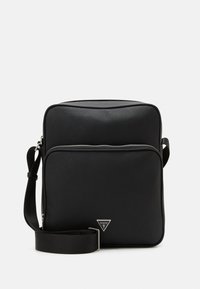 Sac à épaule synthétique noir avec une finition texturée, présentant une poche zippée à l'avant, une sangle réglable et un accent de logo en triangle.