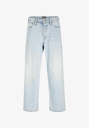 Veste bomber en satin noir avec des boutons pression, t-shirt blanc en dessous, jeans bleu clair et baskets noires avec des accents blancs.