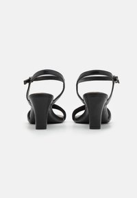 Black heeled sandals with a smooth leather finish, open toe, ankle strap, and a sturdy block heel. Minimalist design with clean lines.