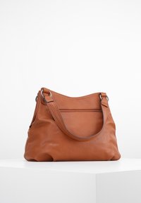 Bruine leren handtas met een zachte textuur, slungelige vorm en een enkele schouderband. Bevat een ritsvak aan de voorkant voor extra opbergruimte.