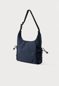 Sima nejlonból készült tengerészkék válltáska, lekerekített formával, állítható pánttal és húzózsinóros részletekkel az oldalakon.