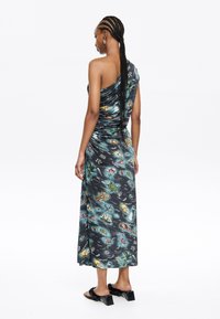 Asymmetric one-shoulder dress in dark fabric with colorful patterns of marine life, featuring a ruched design and ankle-length hem.