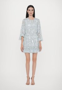 Abito azzurro chiaro con paillettes, maniche a tre quarti, orlo svasato e motivi intricati; il strato trasparente aggiunge texture e dettagli.