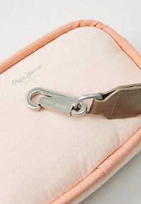 Pepe Jeans pung i lys pink med en orange kant, præget af en quiltet tekstur og et sølvfarvet metalspænde med brandingdetalje.
