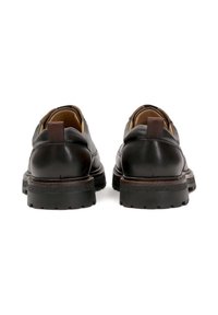 Pantofi din piele neagră cu vârful rotund, talpă din cauciuc rezistentă și accent maroniu la călcâi. Include un etichet pentru o purtare ușoară. Finisaj texturat.
