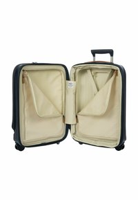 Valigia rigida nera aperta con interni in tessuto beige, scomparti con zip, cinghie regolabili e manico telescopico esteso.