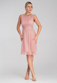 Różowa sukienka bez rękawów z dopasowanym gorsetem i marszczeniem w talii, przechodząca w spódnicę do kolan uszytą z lekkiego, strukturalnego materiału.