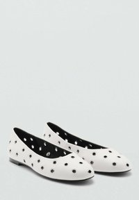 Weiße Ballettschuhe mit runden Ausschnitten, schwarzem Innenfutter und flachen Sohlen. Glatte Oberfläche mit metallischen Akzenten um die Ausschnitte.