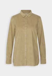 Camisa de pana marrón claro con mangas largas, botón delantero y cuello clásico. Textura suave y detalle de dobladillo redondeado.