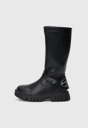 Botte noire en cuir montée jusqu'au genou avec une semelle en caoutchouc épaisse, sangle latérale avec des accents métalliques et texture lisse. Détails de couture le long du corps.