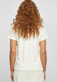 Kortermet, kremfarget topp laget av myk, teksturert stoff, med en avslappet passform og et enkelt, minimalistisk design.