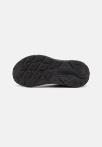 Sole di scarpa sportiva nera con motivo a rilievo caratterizzato da diverse forme e scanalature per migliorare la presa e la stabilità. Logo HOKA presente.