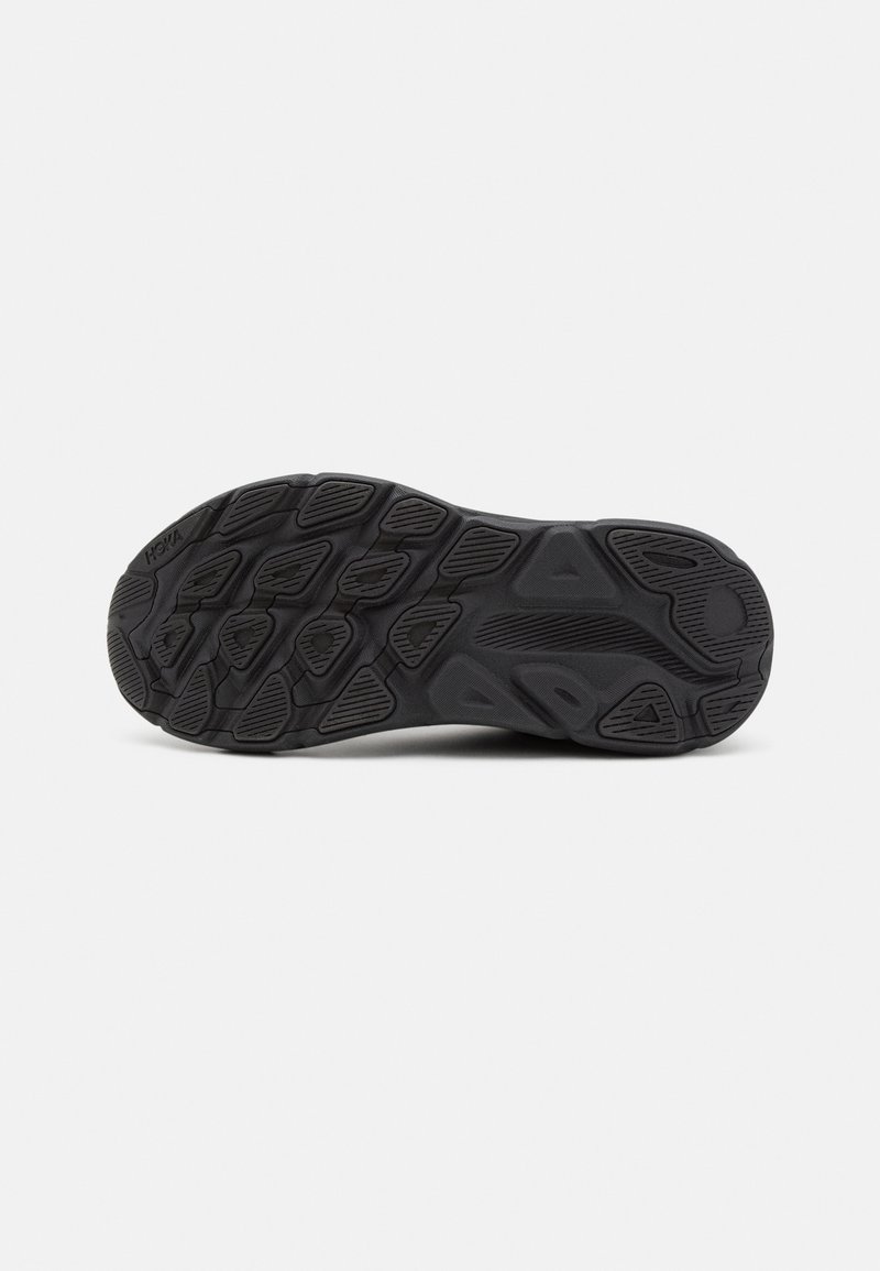 Schwarze Sportschuhsohle mit strukturiertem Profil, das unterschiedliche Formen und Rillen für Grip und Stabilität aufweist. HOKA-Logo vorhanden.